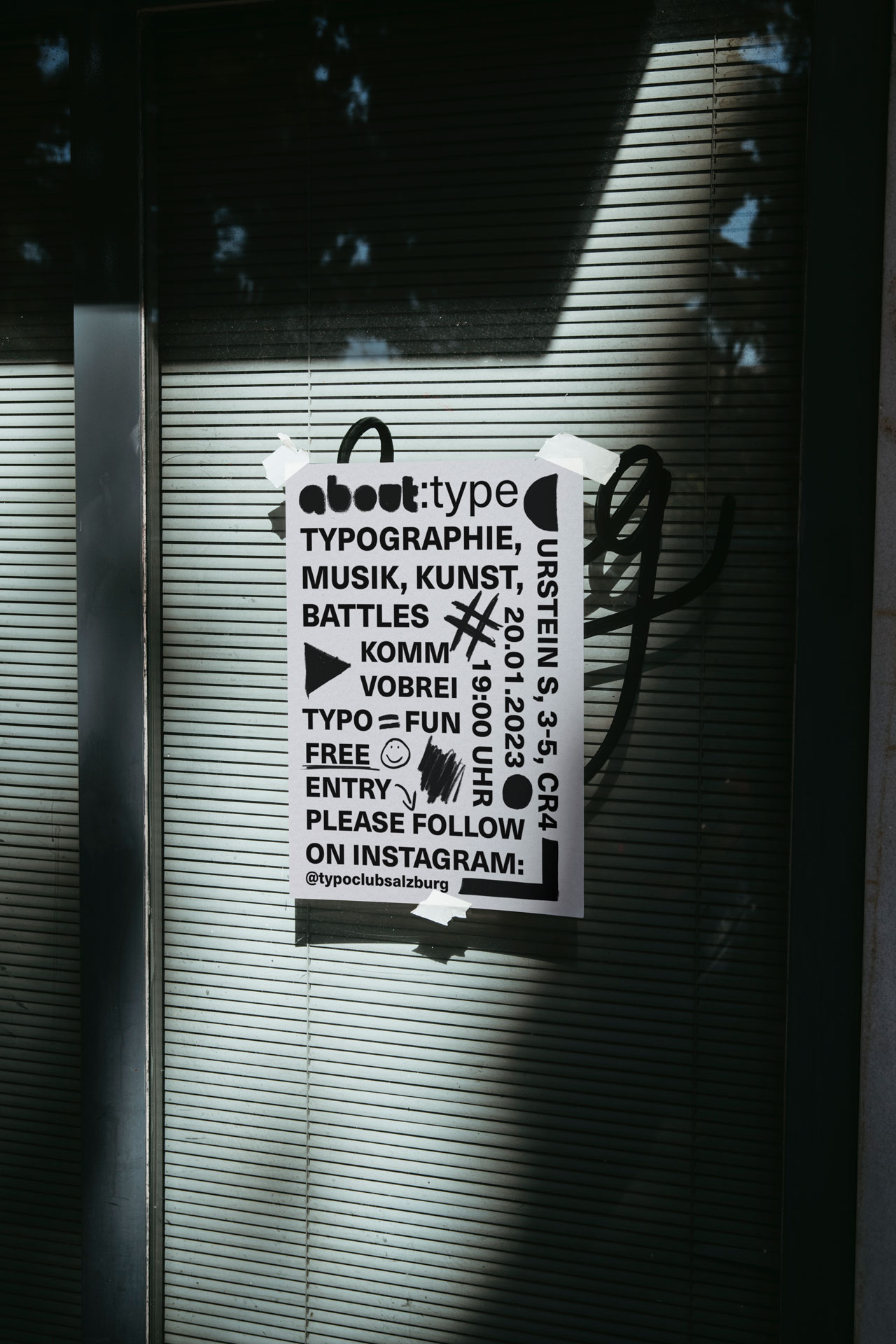 Analog und digital gestaltetes Plakat des Typoclub Salzburg auf einer Glasscheibe mittels Klebestreifen befestigt