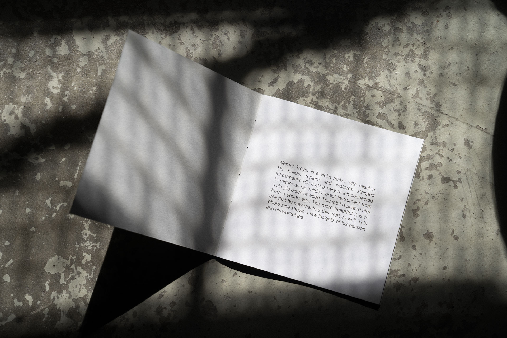 Nahaufnahme von dem geöffneten Violin Maker Fotobuch auf einem rustikalen Steinboden mit Schatten.