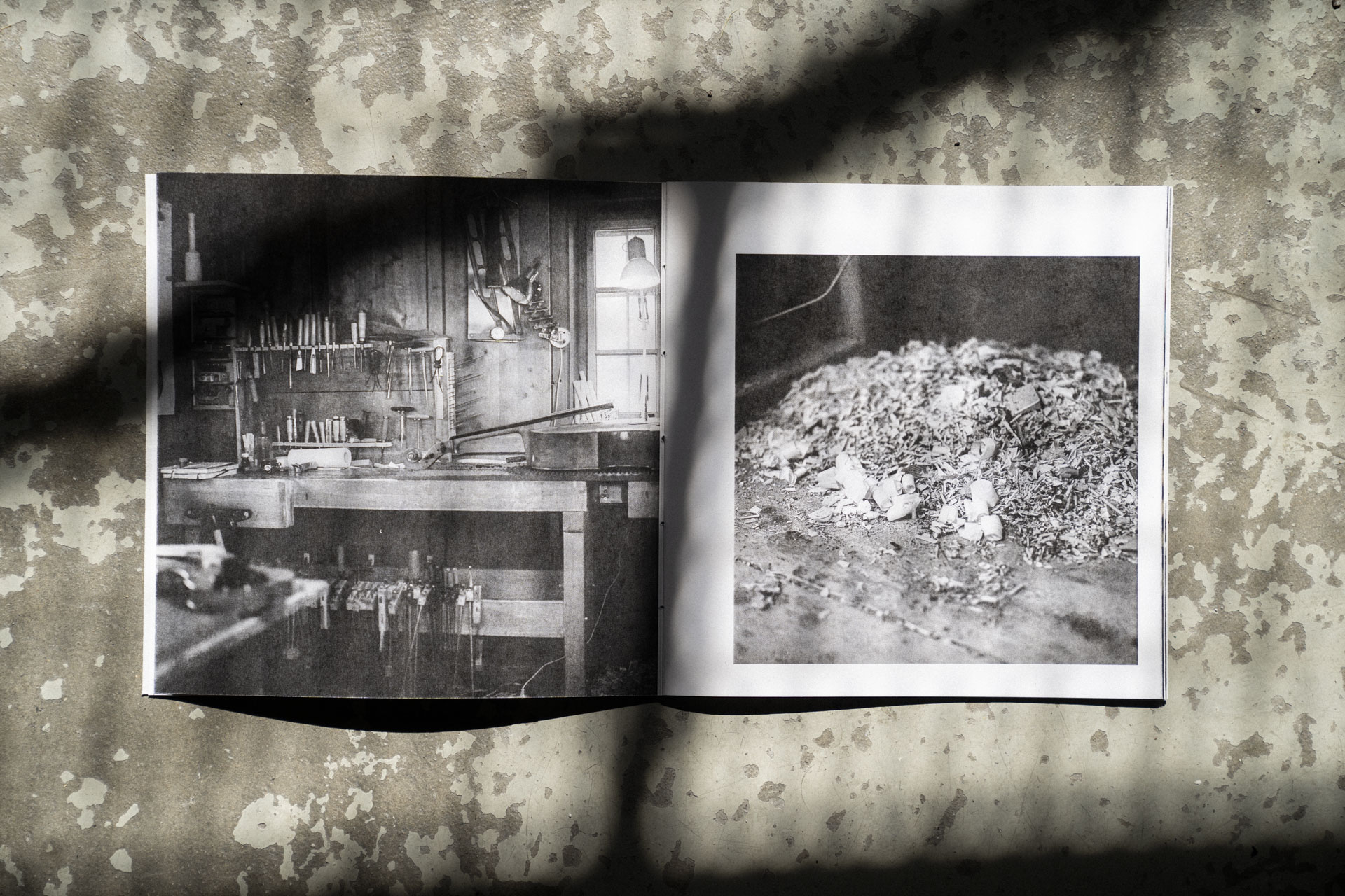 Geöffnetes Violin Maker Fotobuch auf einem rustikalen Steinboden mit Schatten.