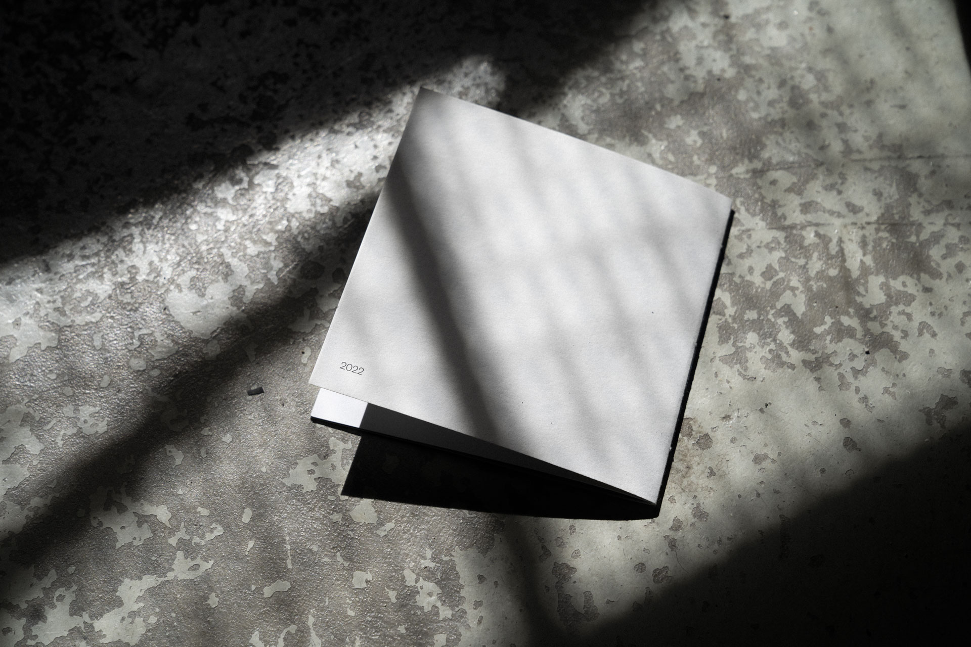 Geschlossene Rückseite vom Violin Maker Fotobuch auf einem rustikalen Steinboden mit Schatten.