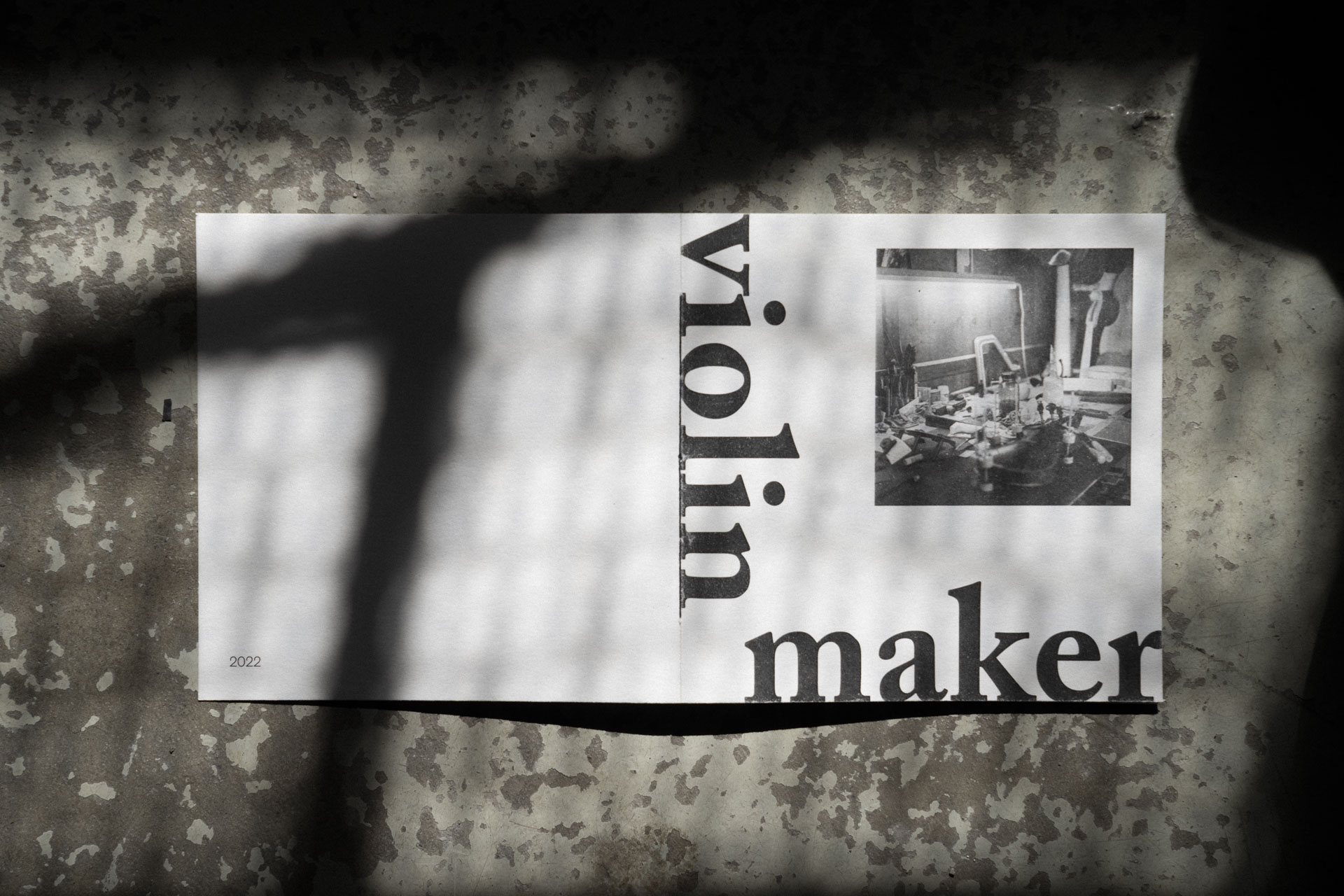 Umschlag des Violin Maker Fotobuch auf einem rustikalen Steinboden mit Schatten.