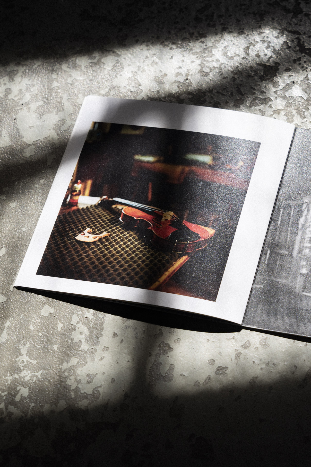 Nahaufnahme einer Seite des Violin Maker Fotobuch auf einem rustikalen Steinboden mit Schatten.
