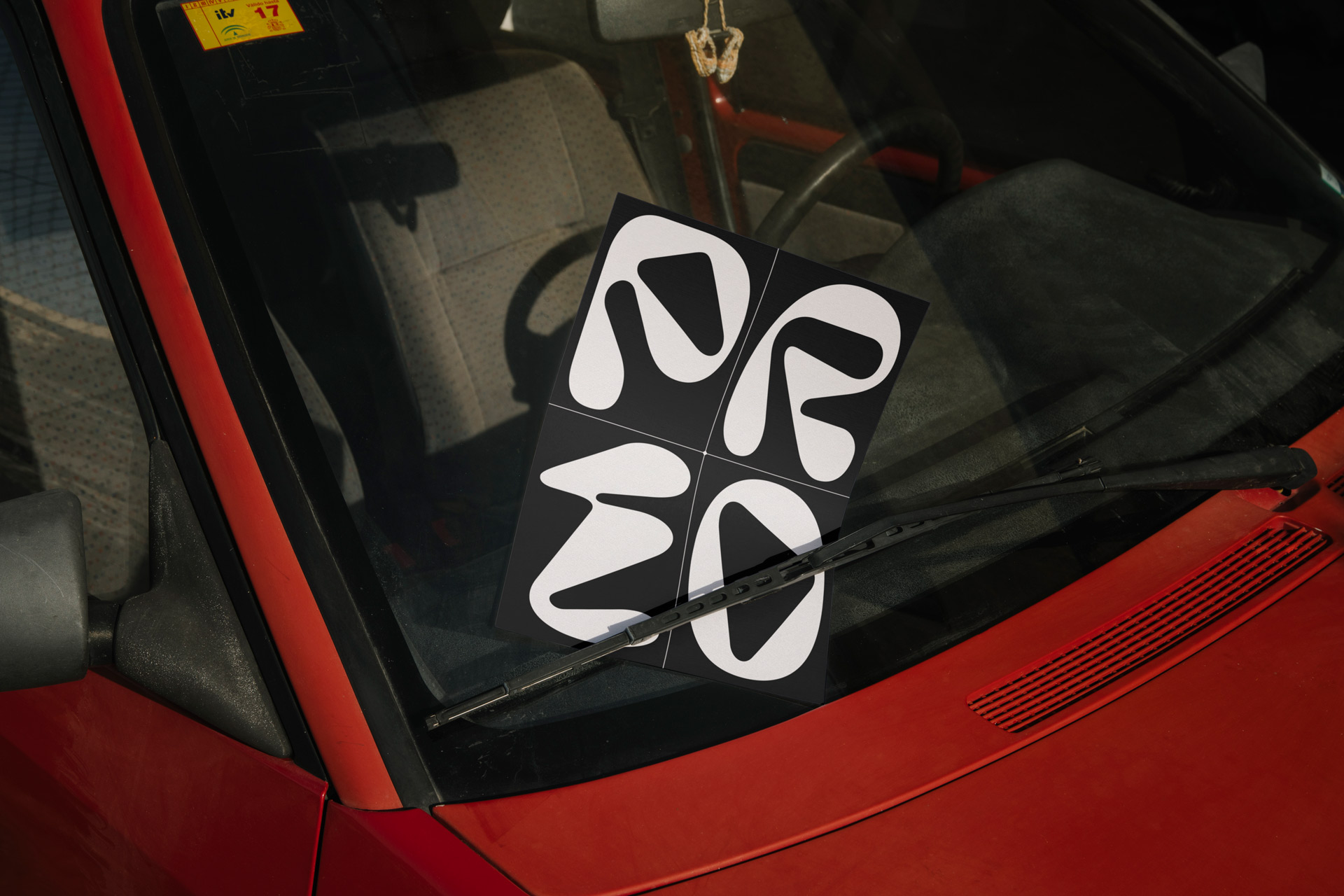 Eine Detailaufnahme eines roten Autos mit einem schwarzen Flyer am Scheibenwischer befestigt.