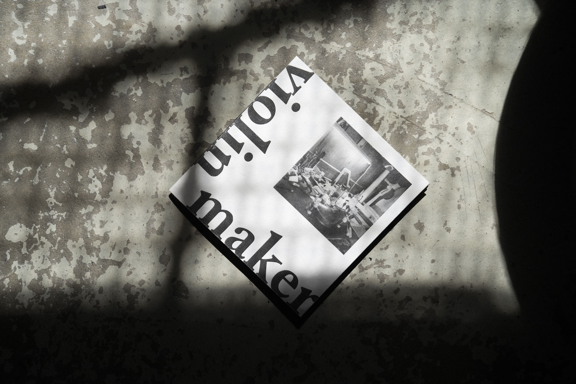 Nahaufnahme von dem Violin Maker Fotobuch auf einem rustikalen Steinboden mit Schatten.